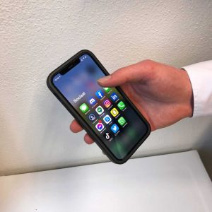 A phone in someone's hand showing all kinds of apps, content channels, JKC Media