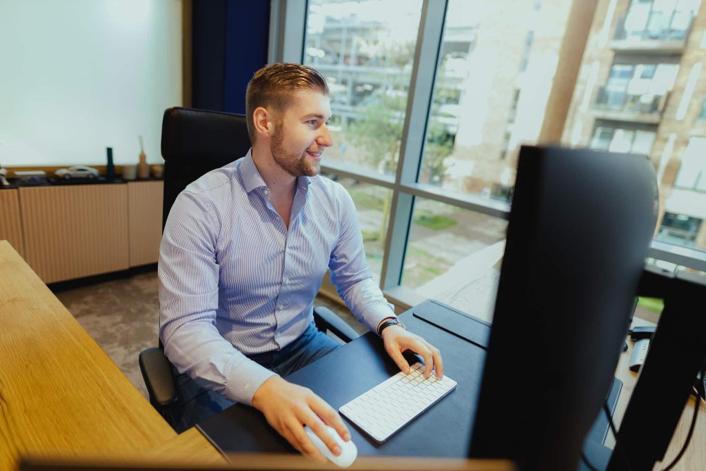A colleague working across two monitors at a standing desk