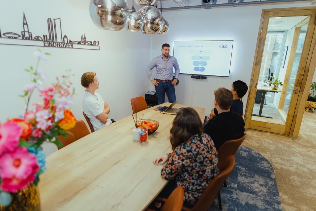 A colleague presenting the See-Think-Do-Care approach to the team in the meeting room