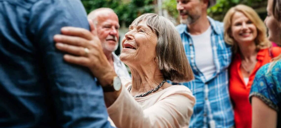 Smiling older woman embracing a family member in a garden