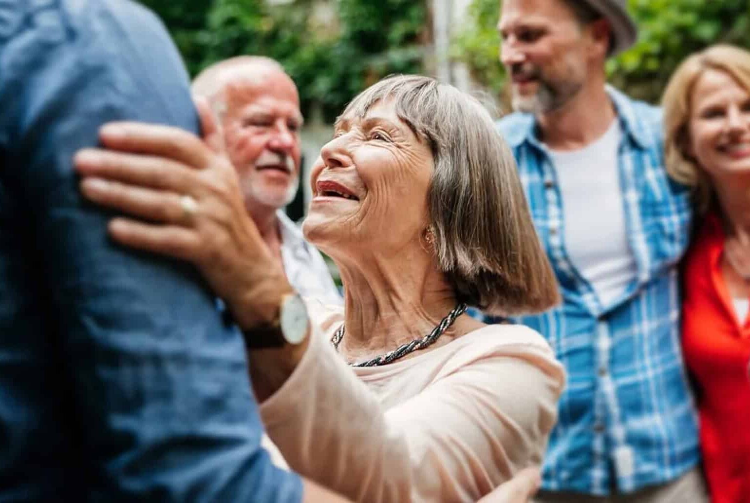 Smiling older woman embracing a family member in a garden
