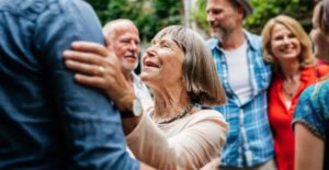 Lachende oudere vrouw die een familielid omarmt in een tuin