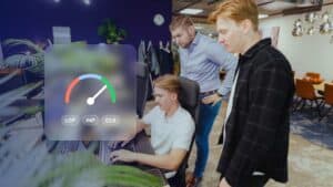 Core Web Vitals: JKC colleagues checking a website together, with a speed gauge and the labels LCP, INP and CLS