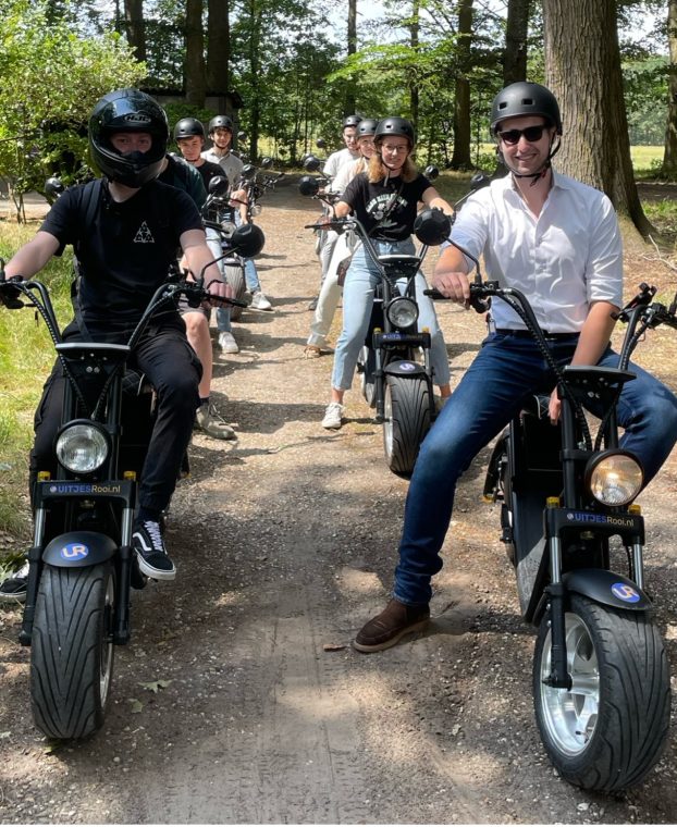 Het JKC-team rijdt op e-choppers over een bospad tijdens het zomeruitje