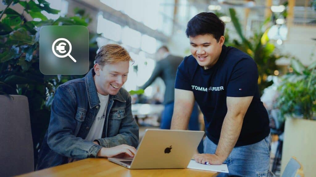 Google Ads cost: two colleagues looking at a laptop, with a magnifying glass and euro icon