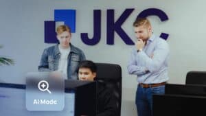 Google AI Mode: JKC Media team looking at a screen together, with an AI Mode search icon