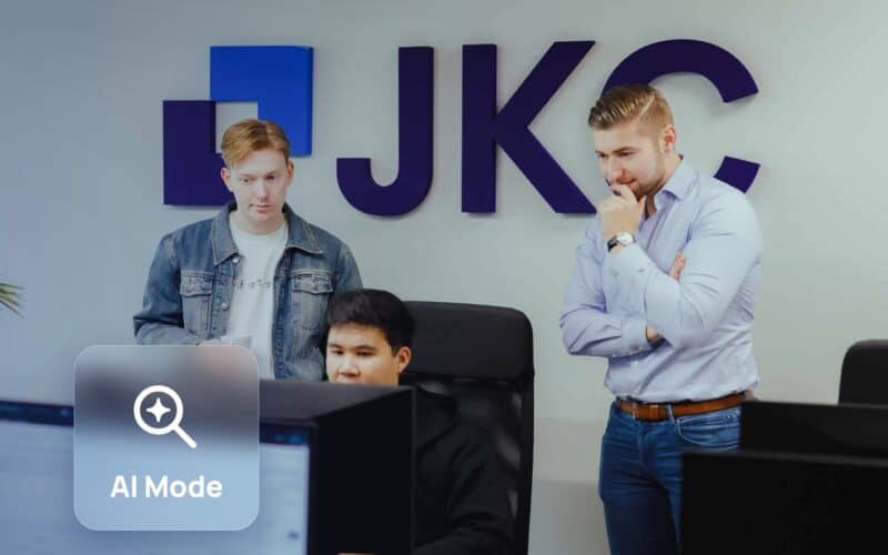 Google AI Mode: JKC Media team looking at a screen together, with an AI Mode search icon