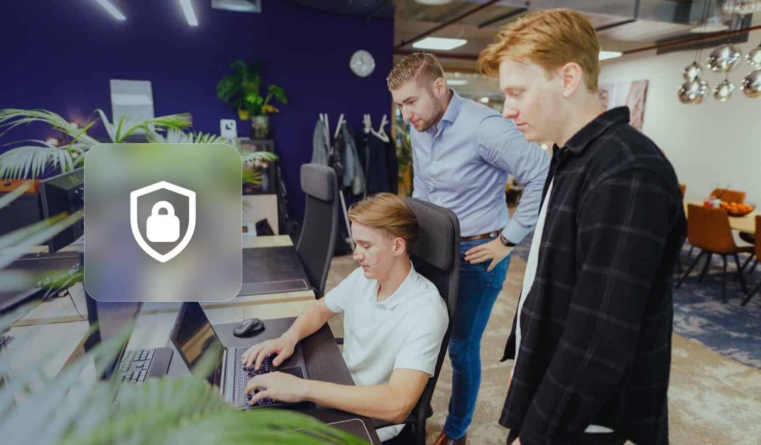 WordPress hacked: three JKC colleagues looking at a laptop next to a shield with a padlock